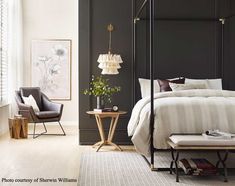 a bedroom with a canopy bed, chair and side table in front of the bed