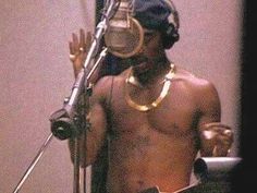 a man with no shirt standing in front of a microphone