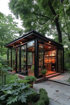 a small glass house in the middle of some trees