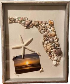 a white frame with shells and starfish on the beach in front of a sunset