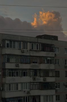 an apartment building with lots of windows and balconies in front of a cloudy sky