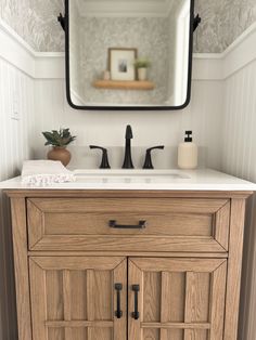 a bathroom vanity with a mirror above it and a plant on the sink counter top