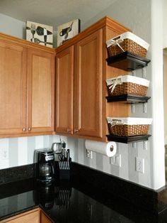 a kitchen with wooden cabinets and baskets on the wall above the stove top, next to a coffee maker