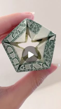 a hand holding a dollar bill origami ring with the video playing on it