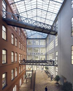 an atrium with people walking and sitting on the benches in front of windows that are lit up