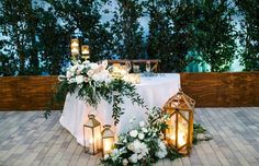 a table with candles, flowers and lanterns on it is set up for a wedding reception