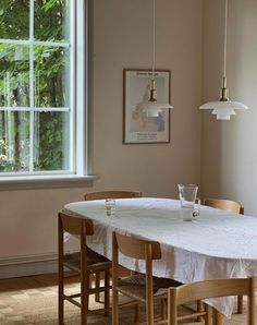 a dining room with a table and chairs in front of a window that has trees outside