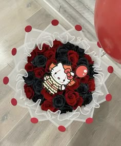 a hello kitty cake surrounded by red and black roses