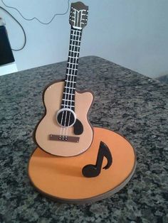 a guitar shaped cake sitting on top of a counter next to a cell phone charger