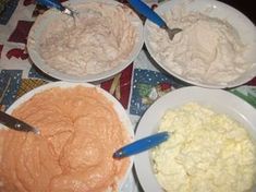 four bowls filled with food on top of a table next to plates and utensils