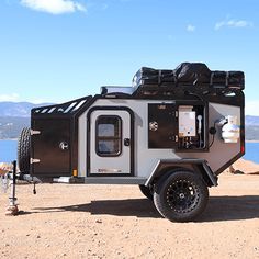 an off road camper parked on the side of a lake