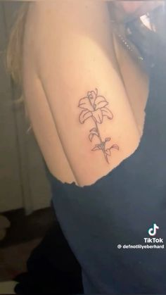 a woman's arm with a flower tattoo on the left side of her shoulder