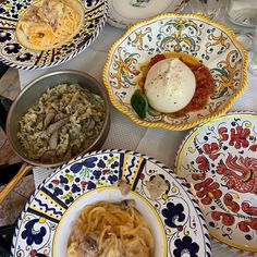 several plates with different types of food on them, including pasta and an egg in the middle