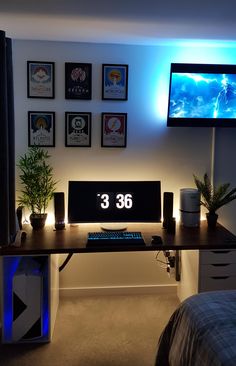 there is a desk with a clock on it and some plants in front of the monitor