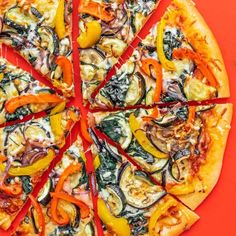 a pizza with many different toppings cut into eight slices on a red surface,