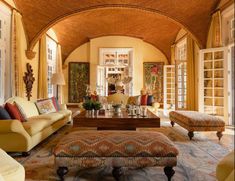 a living room filled with lots of furniture next to large windows on either side of the wall