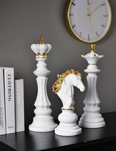 three white and gold chess pieces sitting on top of a table next to a clock