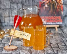 a table topped with glasses and jugs filled with liquid next to a wooden stick