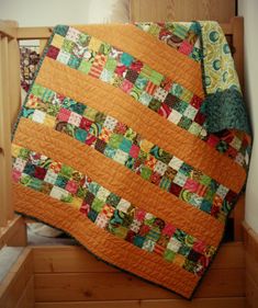 an orange and green quilt on top of a wooden crib