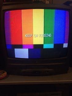 an old television with the words keep on kissing written on it in front of a colorful tv screen