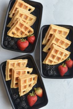 three black plates with waffles and strawberries on the plate next to each other