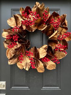 a wreath with red berries and leaves is hanging on the front door's black door