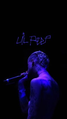 a man with tattoos on his chest holding a microphone in front of a dark background