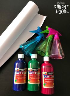 three bottles of paint next to a roll of paper