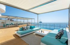 a living room filled with furniture on top of a wooden floor next to the ocean