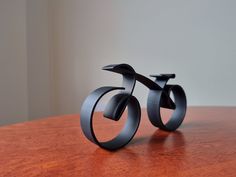 two black sculptures sitting on top of a wooden table next to each other and one is shaped like a bike