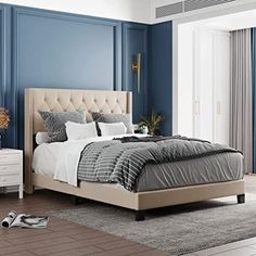 a large bed sitting in a bedroom next to a dresser and window with blue walls