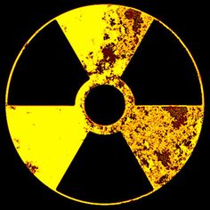 an old yellow and black radioactive symbol on a black background with rusted edges to the bottom