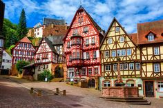 an old european town with half - timbered buildings and fountain in the center, surrounded by cobblestone streets