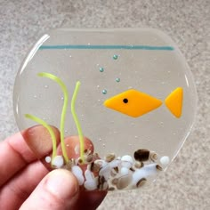 a hand holding a small glass fish bowl