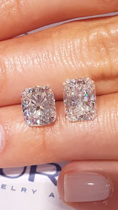 a woman's hand with two diamond earrings on her left and the other hand holding an engagement ring