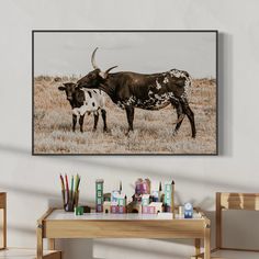 a cow and calf standing in an open field with paintbrushes on the table