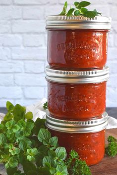 three mason jars stacked on top of each other filled with homemade canned pizza sauce and herbs