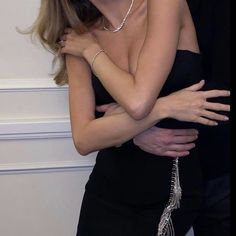 a man and woman embracing each other in front of a wall with pearls on it