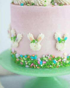 there is a pink cake with white frosting and decorations on the top, sitting on a green plate