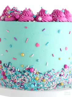 a blue cake with sprinkles and pink frosting on it's top