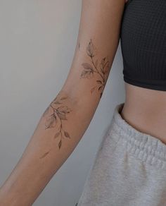 a woman's arm with leaves on it and a tattoo design on the wrist