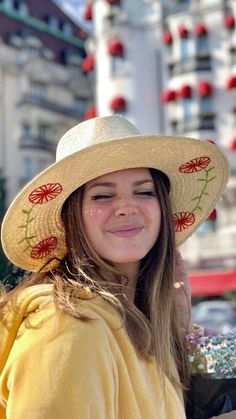 a woman wearing a hat and holding flowers