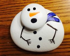 a painted snowman sitting on top of a wooden table