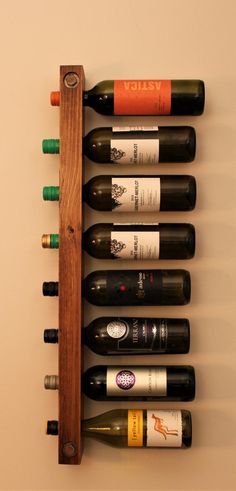 a wooden wine rack holding six bottles of wine and two empty ones on the wall