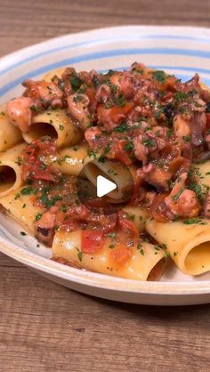 a pasta dish with meat and sauce on a blue and white striped plate sitting on a wooden table