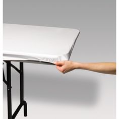 a hand is holding the edge of a table with a sheet on it that has been folded over