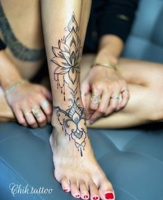 two women with tattoos on their legs sitting next to each other and one has a flower tattoo on her left foot