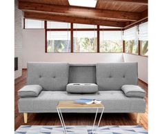 a grey couch sitting on top of a wooden floor next to a table and windows