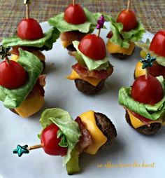 mini burgers with cheese, tomato and lettuce are arranged on a plate