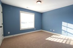 an empty room with blue walls and carpeted flooring is seen in this image